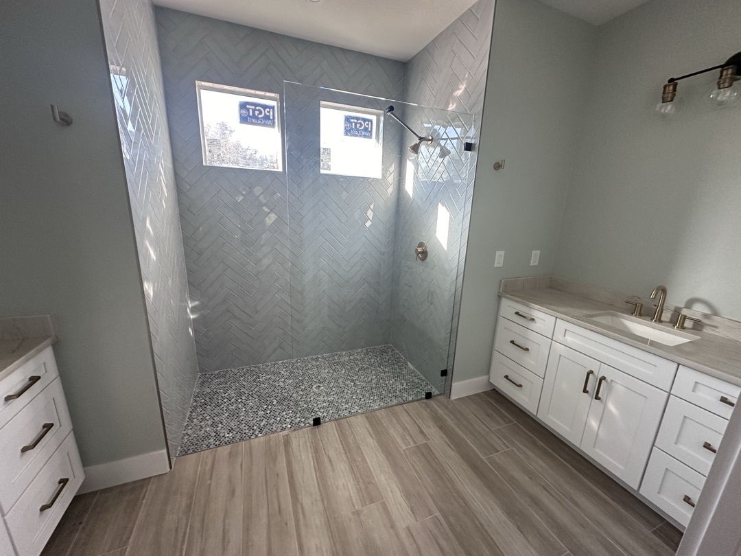 Gray tile shower with built-in bench and mosaic accent