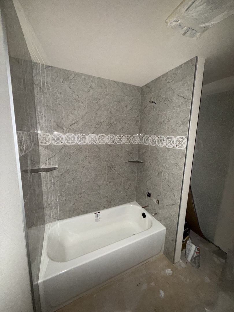 Light gray marble bathtub surround with decorative border