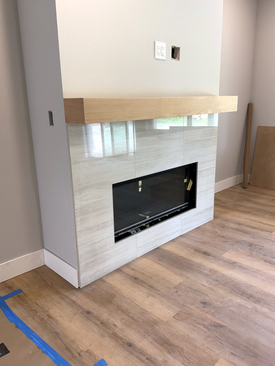 Large-format cream marble-look tile fireplace with floating wood mantel